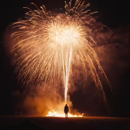 a man standing in front of firework on a field