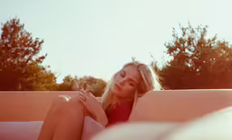 the woman is sitting on a pink couch