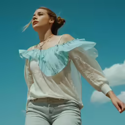 a woman in white top and jeans looks up at the sky