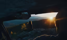 a person standing next to a car looking out at the sun