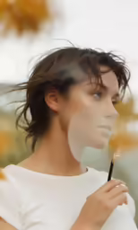 woman in white shirt blowing on colorful stick