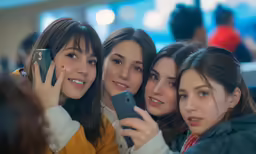 three women holding their cell phones up in front of them