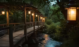 a bridge with lantern lights leading to a stream