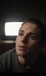 the man stares into the distance in a darkened room