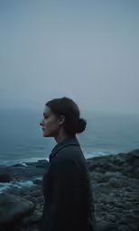 a woman stands in front of the ocean
