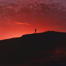 a man on top of a hill with the sky in the background