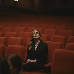 a woman sitting in an auditorium with her arms crossed