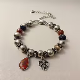 an adjustable bracelet with a leaf and charm,a bracelet has a charm attached to it
