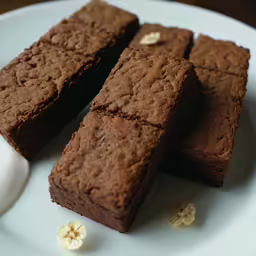 a white plate topped with three brownies next to an egg