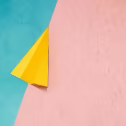 a yellow triangle resting on top of a pink surface