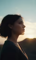 a woman looking at the horizon with the sun behind her