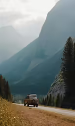 a vehicle is on a dirt road with mountains in the background