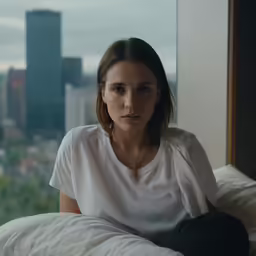 a woman sitting in bed next to a window