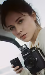 a woman is looking at her camera while holding her cellphone