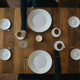 a group of people sitting around a table with dishes and cups on it