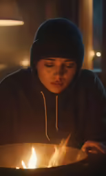 a man sitting on the floor in front of a frying pan holding a lit candle