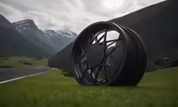 black wheel on grassy field near road in mountains