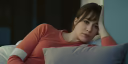 the young woman is lying on her bed looking at the camera