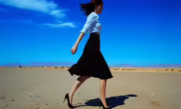 a woman in a skirt and shirt walking across sand