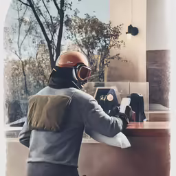 person wearing helmet with gloves on standing in front of counter with laptop