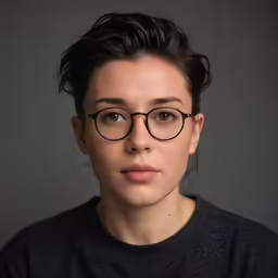 a woman with black glasses and a top knot