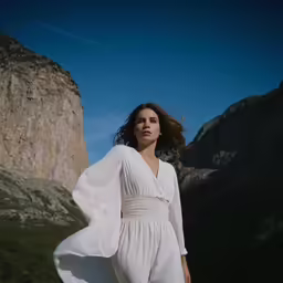 a woman standing in the mountains wearing white