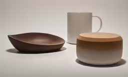 two wooden dishes and a cup that is next to each other