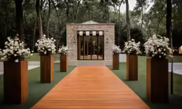 a wooden walkway is next to a brick building and some flowers