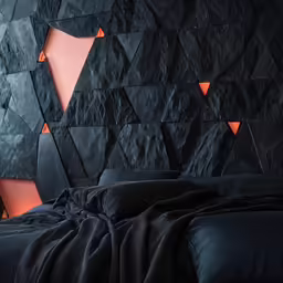 black bed in a room with a stone wall