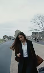 a woman walking down a city street next to buildings