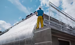 a man wearing a hard hat walking up a slope to a structure