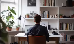 a person is sitting in a chair at a computer desk in front of shelves with books