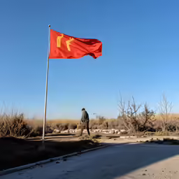 the man is walking down the road towards the red flag