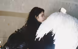 a girl in black jacket with angel wings next to a motorcycle