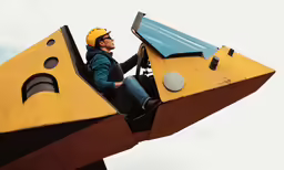 a man in a yellow helmet sits on a giant piece of concrete