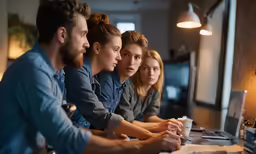 a group of people are staring at something on the computer