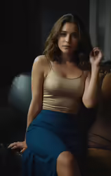 the woman is wearing a light colored top and a blue skirt