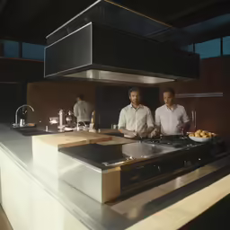 two men standing in a kitchen preparing food