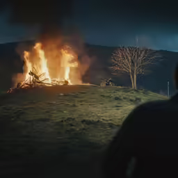 a person in the distance watching a fire that is blazing