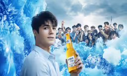 a young man holding a bottle of beer in front of a large crowd