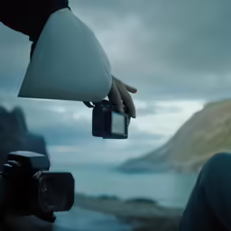 a person holding an object in their hand while looking at the ocean