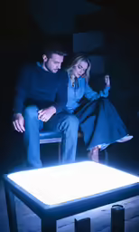 man and woman sitting on chair next to lit table