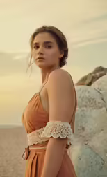 the woman is wearing an orange dress on the beach