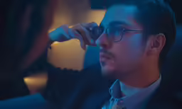 the man is adjusting his glasses while sitting down