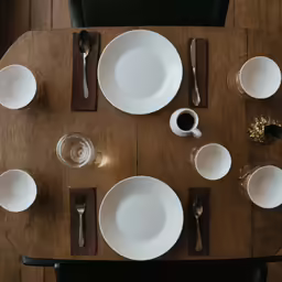 dinner place setting on wooden table with black utensils