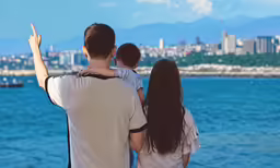 a family looking out over the ocean with their arms extended