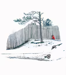 a man sitting in front of a wooden fence