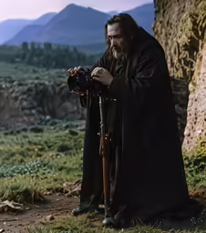 a man wearing a black robe is holding a camera