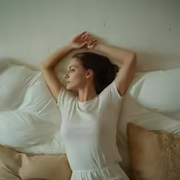 a beautiful young lady laying on top of a bed