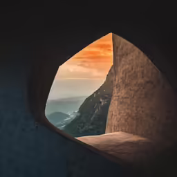 a window opening revealing a view of some mountains and trees
